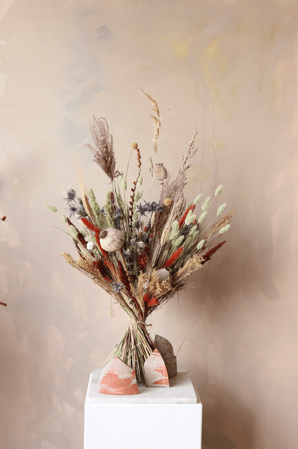 dried flower bouquet in autumnal colours. Includes poppyseed, thistle, grasses, broom. Colours are blue, green orange and red
