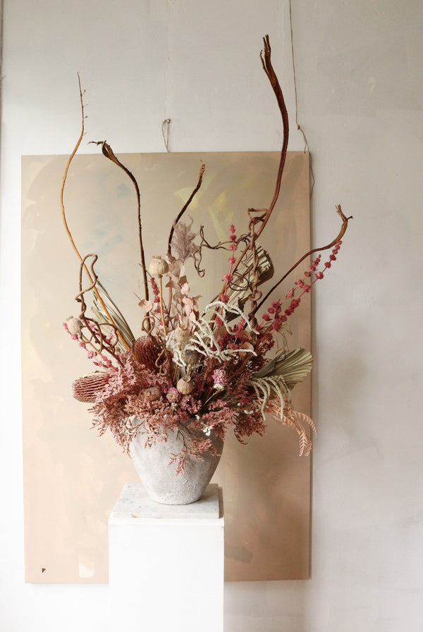 Large dried flower arrangement in pink flowers and concrete vase